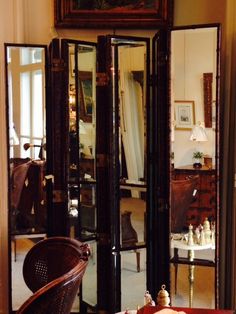 an ornate room divider in front of a mirror with chess pieces on the table