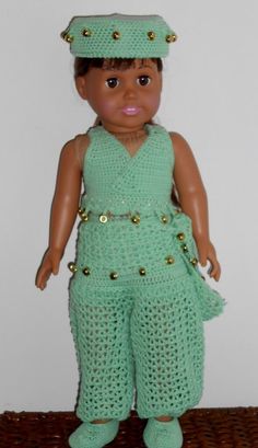 a doll wearing a green crochet outfit with gold buttons on it's head