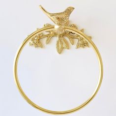 a gold bracelet with a bird perched on it's side and leaves attached to the clasp