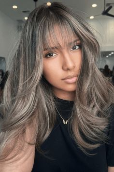 This hairstyle showcases a layered cut with voluminous, tousled waves, emanating a relaxed yet stylish aura. The ash blonde base is skillfully accented with subtle, sun-kissed highlights, adding depth and dimension to the overall look. The face-framing highlights, especially around the bangs, draw attention to the eyes and soften the - Click to see more of Upgrade Your Look with 36 Stunning Hair Highlight Picks and follow us for more hairstyle ideas. // Photo Credit: Instagram @hairbyjess_1 Hair Color With Bangs Highlights, Blonde And Ash Highlights, Brunette Hair Ash Highlights, Ash Blonde Highlights Dark Hair, Ashy Grey Highlights, Blonde With Grey Highlights, Dark Hair Ashy Highlights, Blended Gray Hair With Highlights, Bangs With Blonde Highlights