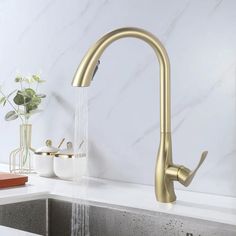 a gold faucet with water running from it's spout in a kitchen