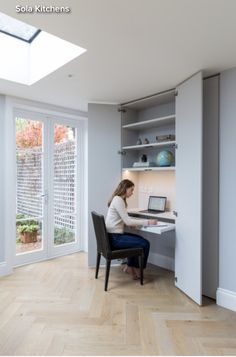 a woman sitting at a desk in front of a window with a laptop on it