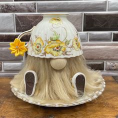 a white and yellow hat with flowers on it sitting on top of a wooden table