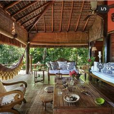 an outdoor living area with couches, tables and hammock hanging from the ceiling