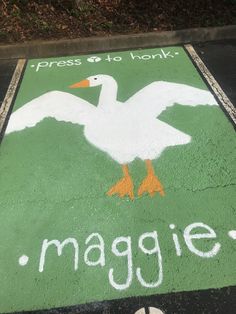 a sign painted on the ground that says imagine and a white duck with orange feet