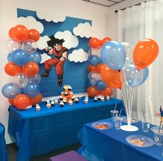 a table topped with balloons and cupcakes next to a blue table cloth covered wall