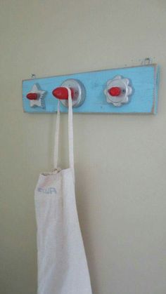 a white bag hanging on a blue coat rack with two red knobs attached to it