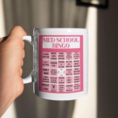 a person holding a coffee mug with the words med school bingo written on it in pink