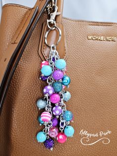 a handbag with many colorful beads hanging from it's front pocket and a long metal keychain