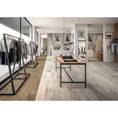 an empty clothing store with clothes on racks and wooden tables in front of them,