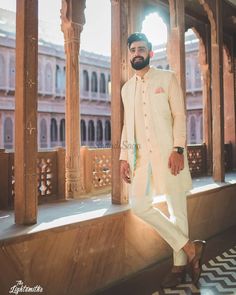 a man in a white sherwar standing on a balcony