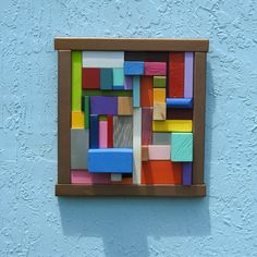 a multicolored piece of wood mounted to the side of a blue painted wall