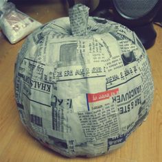 a newspaper pumpkin sitting on top of a wooden floor