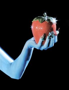 a person holding an apple in their hand with blue skin and nail polish on it