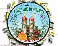 a christmas card with two candles surrounded by greenery and an orange on the side