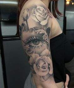 a woman's half sleeve with roses and an eye tattoo on her left arm