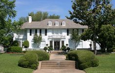 a large white house surrounded by trees and bushes