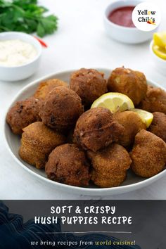 a white bowl filled with fried food next to dipping sauces and lemon wedges