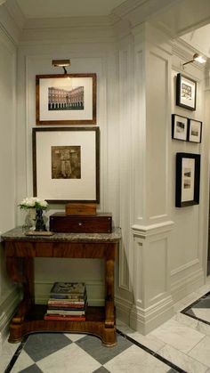 a room with white walls and black and white checkered flooring, framed pictures on the wall