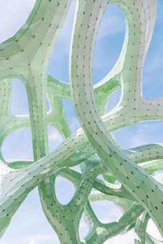 an abstract sculpture with curved lines and dots in the middle, against a blue sky