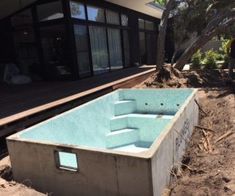 an above ground swimming pool in the middle of a dirt area next to a house