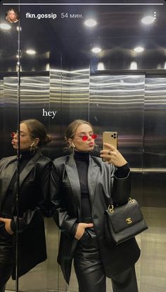 two women standing in front of a mirror taking a selfie with their cell phone