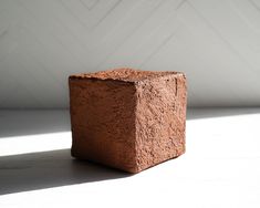 a square brick sitting on top of a white floor next to a wall and window