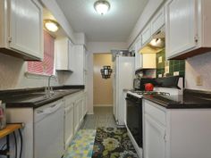 a modern kitchen with stainless steel appliances and black counter tops, along with hardwood flooring