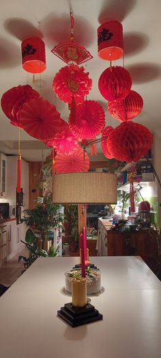 red paper lanterns hang from the ceiling above a table with plates and cups on it