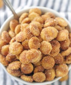 a white bowl filled with sugared donuts on top of a striped table cloth