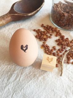 a wooden stamp with a chicken on it next to some beans and a jar full of eggs