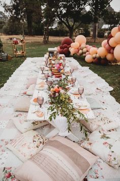 a long table is set up with many pillows and place settings for an outdoor dinner