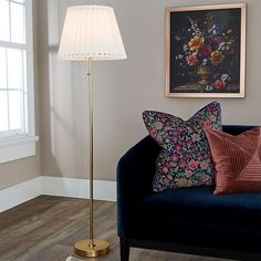 a living room scene with focus on the floor lamp and flowers in the vase behind the couch