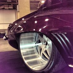 the front wheel of a purple car with chrome rims