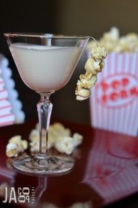 a drink in a glass with popcorn on the table