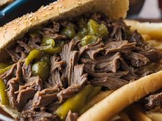 a close up of a sandwich with meat and peppers in it on a plate next to french fries