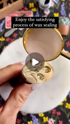 a person is holding a gold cup in their hand with the words, enjoy the satisfactioning process of wax sealing