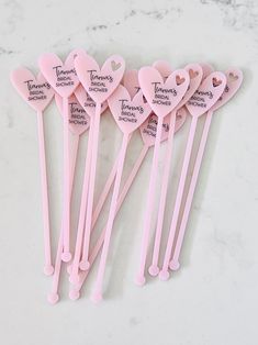 five pink heart shaped spoons with names on them sitting on a marble countertop