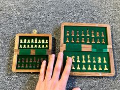 a person's hand next to an open wooden box with chess pieces in it