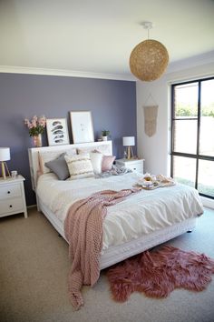 a bedroom with purple walls, white bedding and pink fluffy rugs on the floor