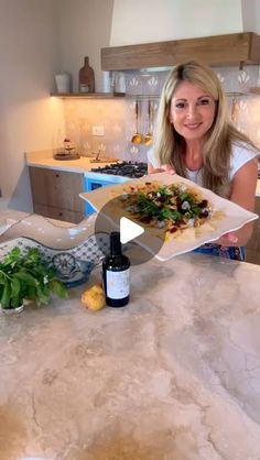 a woman is holding a plate with food on it in the middle of a kitchen