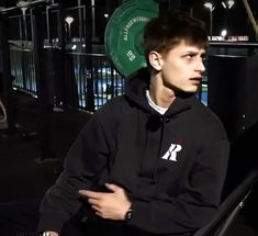 a young man in a black hoodie is sitting down