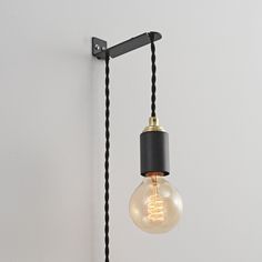 a light bulb hanging from a wall with a black cord attached to it and a white wall in the background