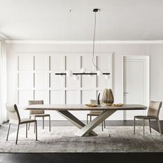 a dining room table with chairs and a vase on top of it in front of a white paneled wall