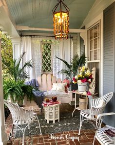 the porch is decorated with white furniture and potted plants