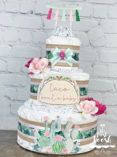 a three tiered cake is decorated with cactus and pink flowers on the bottom layer