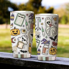 two halloween themed cups sitting on top of a wooden table