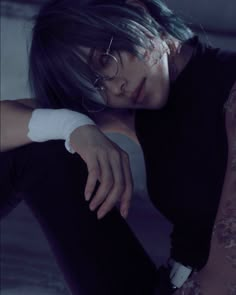 a woman with glasses and bandages on her arm sitting in a dark room next to a wall