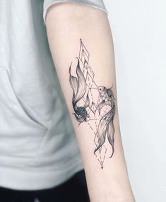 a person with a tattoo on their arm holding up a fish and diamond shaped object