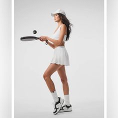 a woman in white tennis outfit holding a racket